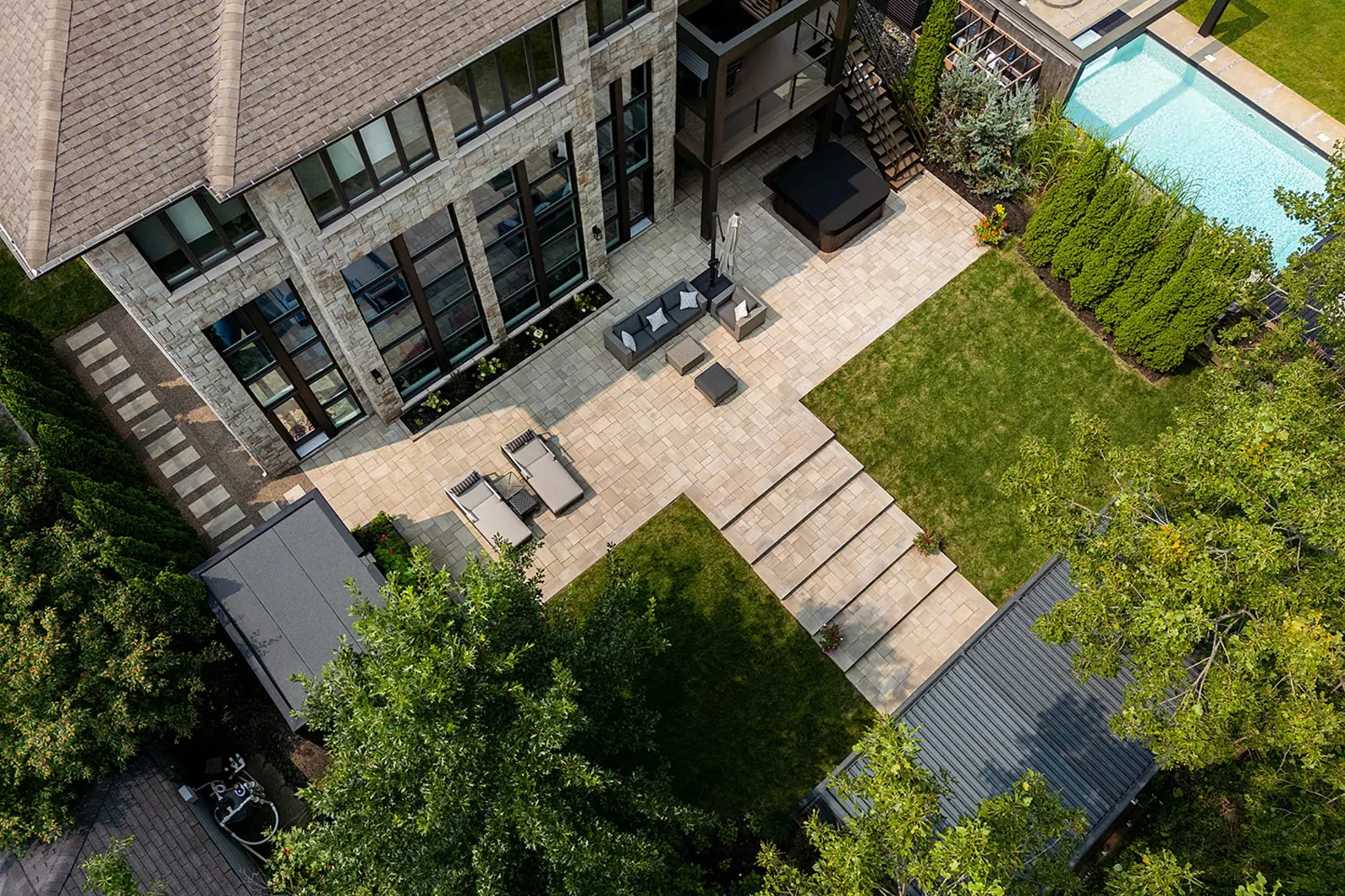 Sloped backyard built in terraces with patios, walls and lawn, aerial view