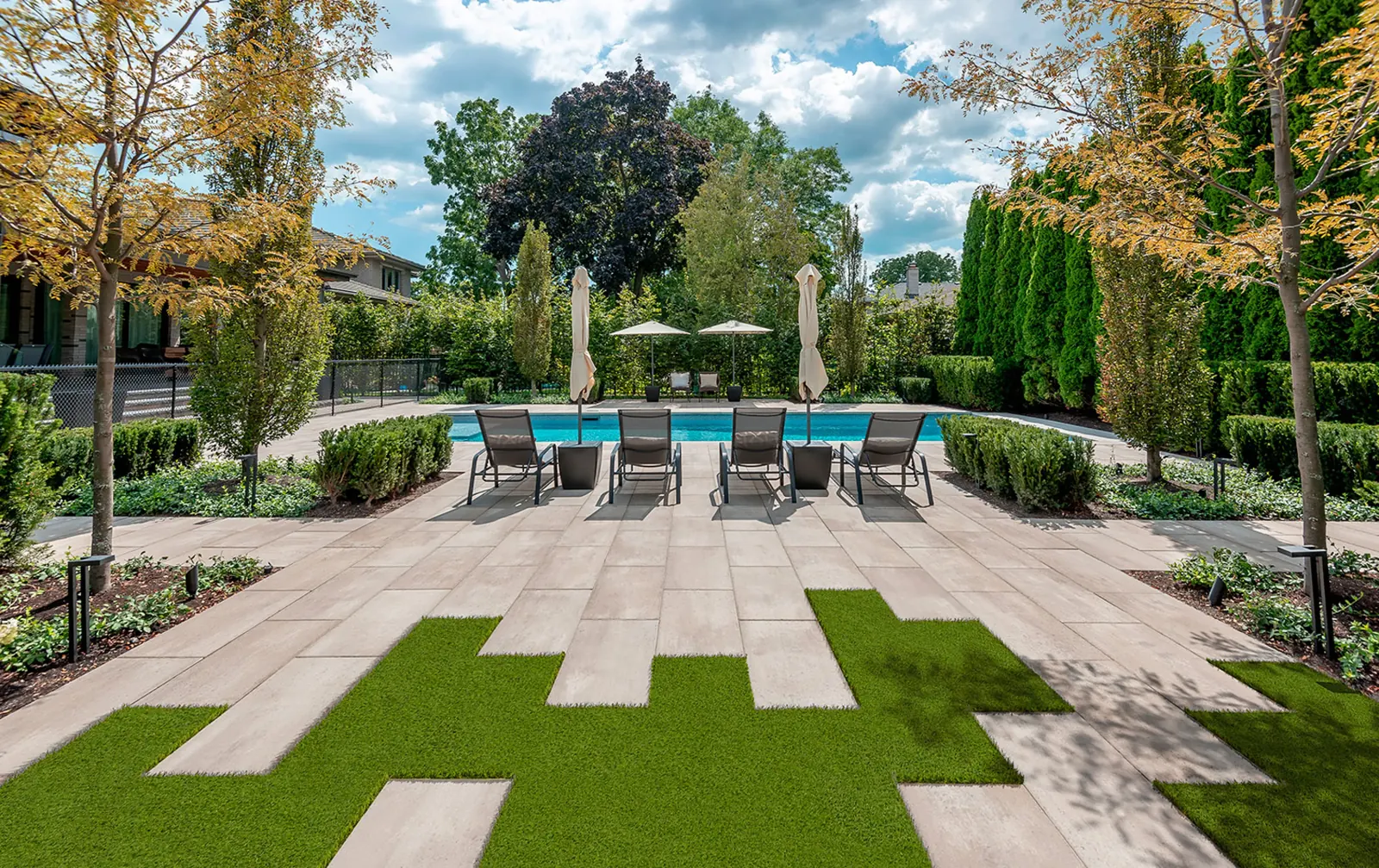 Proma XL slab patio in Oka beige around an in-ground pool, with lawn strips