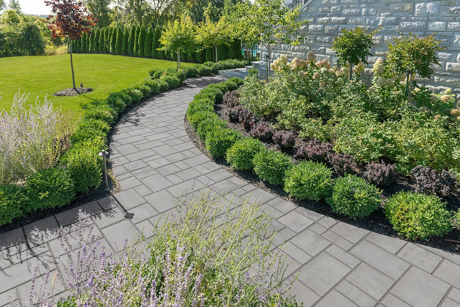 Curved Aspen paver walkway in ash charcoal lined with planting beds